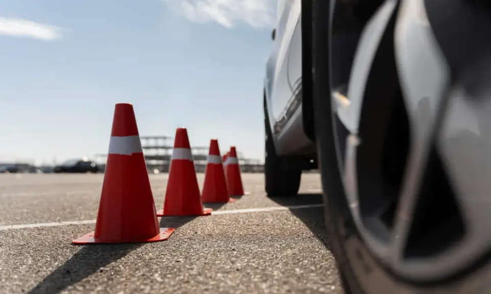 Conos naranjas marcan la zona f para el carnet C. Un coche se acerca, listo para la maniobra.