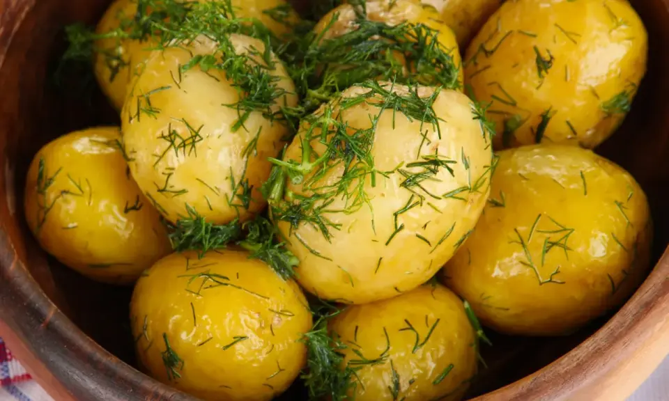 Ziemniaki gotowane w drewnianej misce, posypane świeżym koperkiem. Aromatyczne i apetyczne danie.