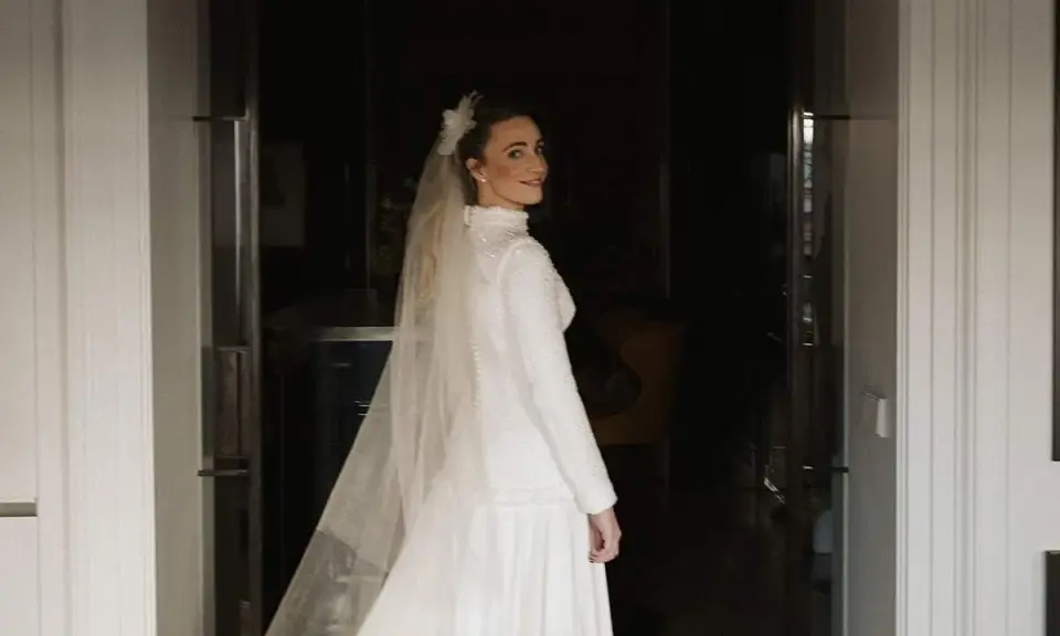Novia sonriente con velo y vestido blanco, parte de un ajuar de novia tradicional, lista para su gran día.