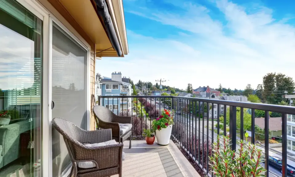 Wygodny balkon z rattanowymi meblami i kwiatami. Inspiracje na płytki na balkon.