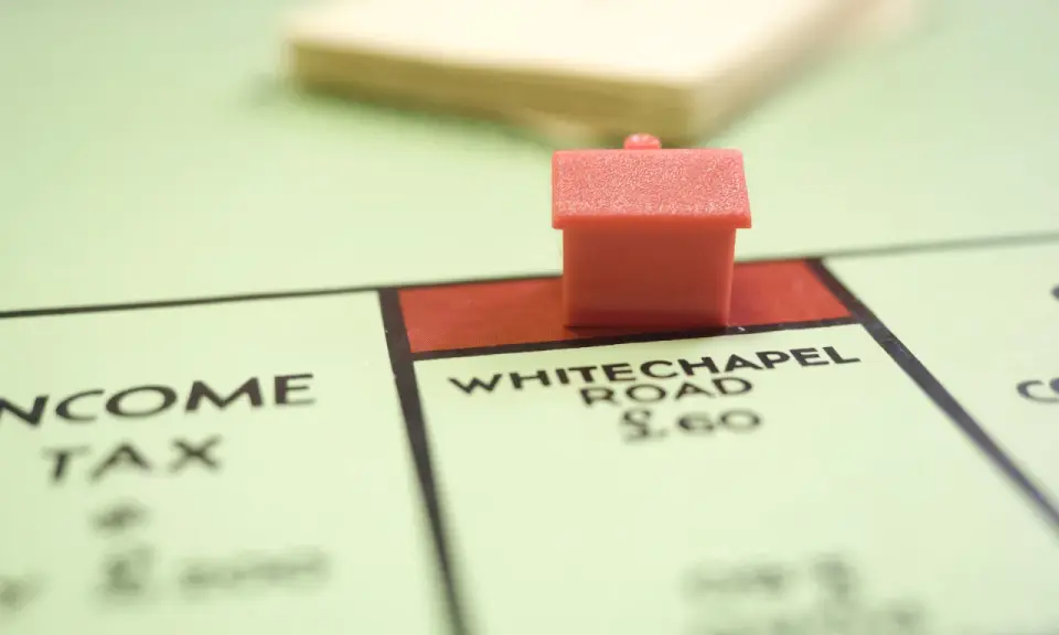 Une petite maison rouge sur le plateau Monopoly, près de Whitechapel Road. Le jeu simule le transfert de prêt.