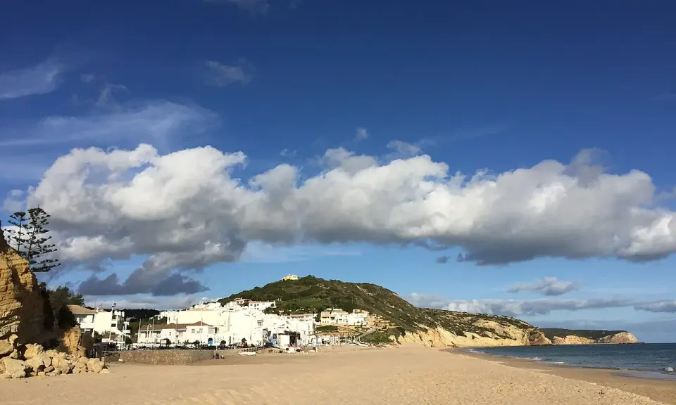 Sonne, Sand und weiße Häuser: Ein malerischer Blick auf Salema, Portugal, mit dem Atlantik und dramatischen Wolken.