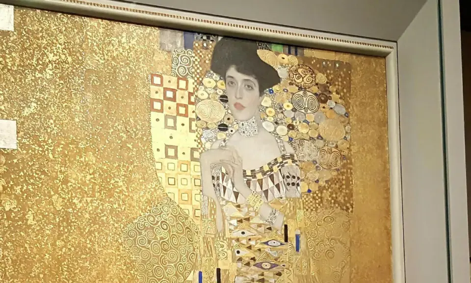 A woman in gold painting, adorned with intricate patterns and jewels, gazes serenely from a gilded background.