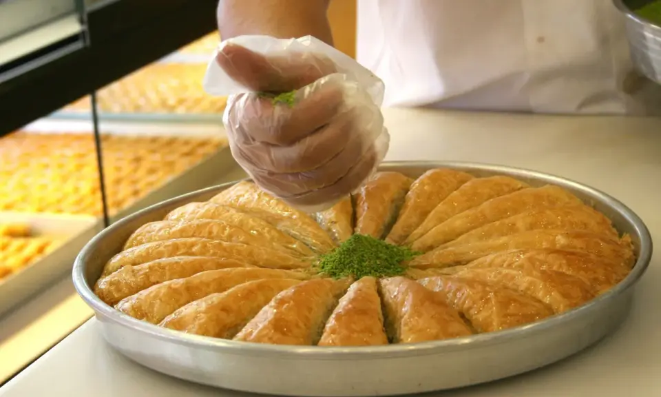 Słodka baklava, co to za przysmak? Warstwy ciasta filo, orzechy i syrop. Posypka z pistacji dodaje uroku.
