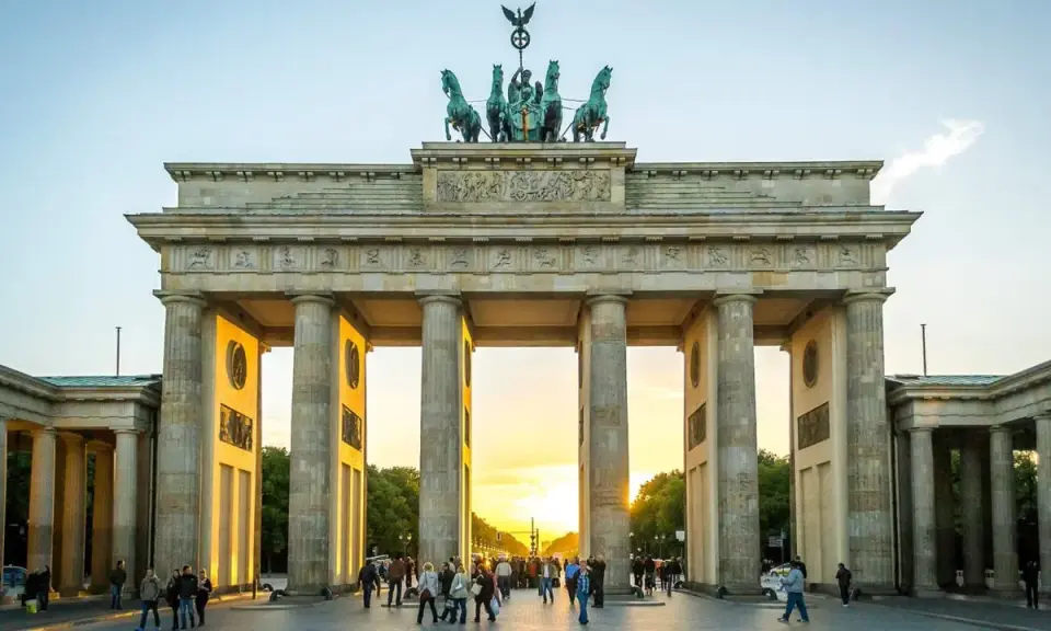 Brandenburger Tor i Berlin, en ikonisk sevärdhet som visar vad man ska se i Berlin. Solnedgången lyser upp monumentet och folklivet.