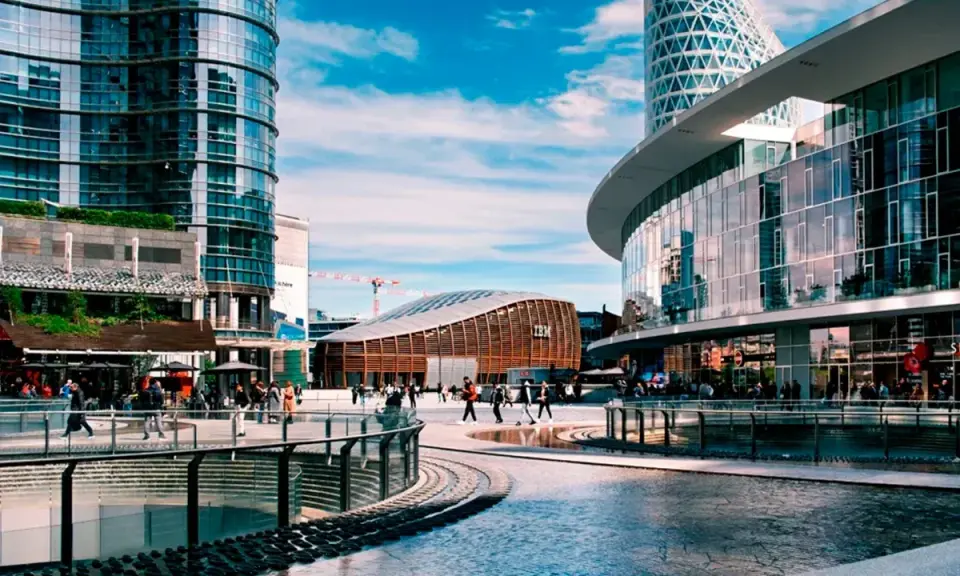 Scena urbana moderna con persone che passeggiano, un edificio IBM e grattacieli specchiati. Immagini di vita quotidiana in una città dinamica.