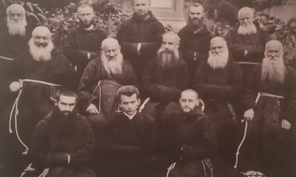 Grupa zakonników w habitach. W środku, w pierwszym rzędzie, siedzi młody mężczyzna, być może to **Honorat Koźmiński** w otoczeniu braci.