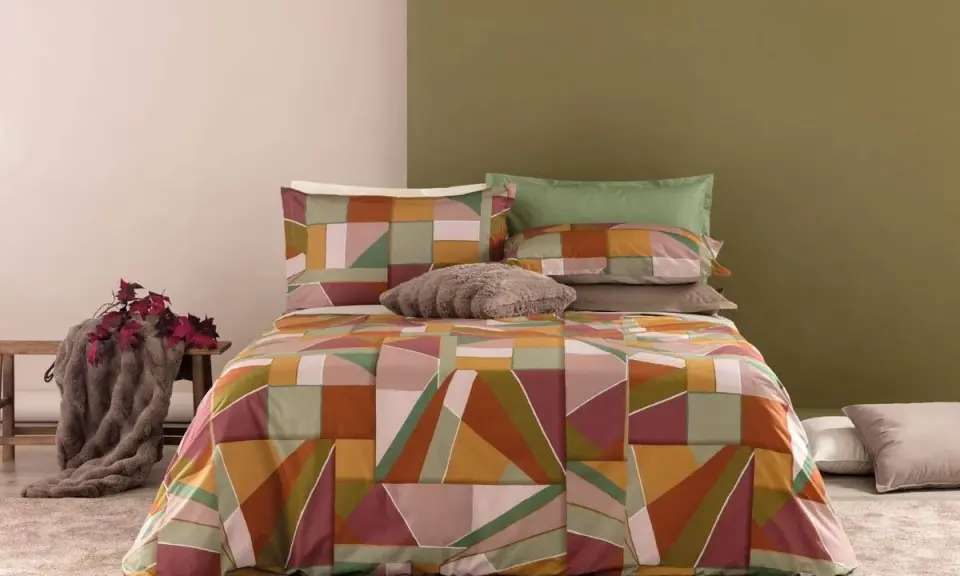 Un letto con copripiumino geometrico dai colori caldi e terrosi. Un perfetto abbinamento colori camera da letto per un tocco moderno e accogliente.
