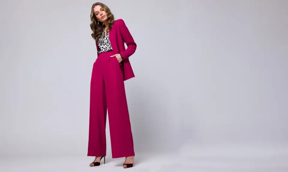 Elegancka stylizacja na chrzciny ze spodniami: fuksjowy garnitur z szerokimi nogawkami i bluzka w panterkę.