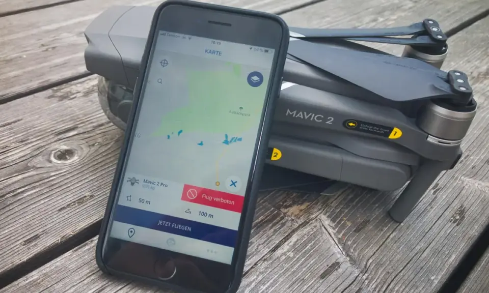 Smartphone mit Drohnen-App zeigt "Flug verboten" neben Mavic 2. Eine droniq app alternative könnte hier nützlich sein.
