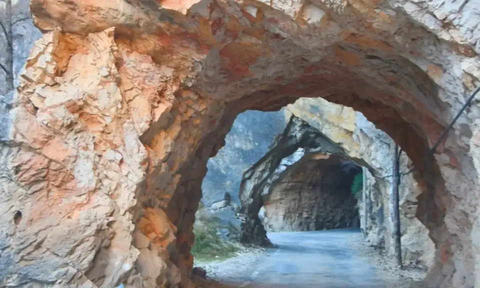 Un túnel natural en la ruta del silencio Teruel, con paredes de roca rojiza y un camino que se adentra en la montaña.