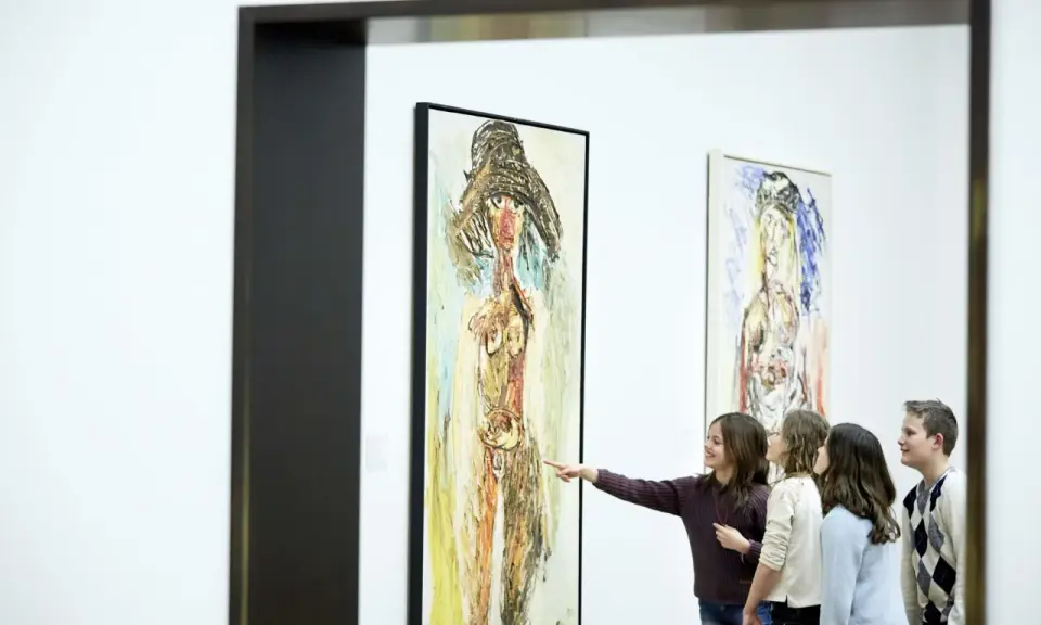 A group of children admire a painting in the style of the cobra art movement, with one girl pointing at the abstract figure.