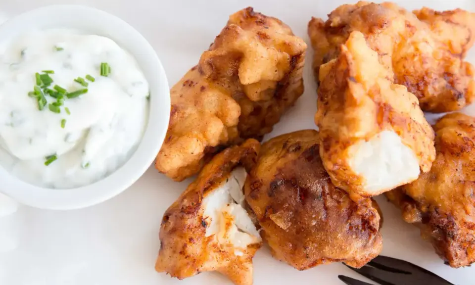 Knusprig frittierte Fischstücke, perfekt für ein Kibbeling Rezept, mit einem cremigen Dip mit Schnittlauch.