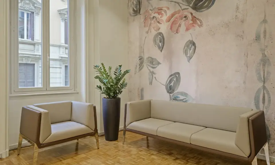 Eleganckie fotele i sofa na tle tapety z motywem kwiatowym. Czy można kleić tapetę na tapetę? Tutaj wygląda to stylowo.