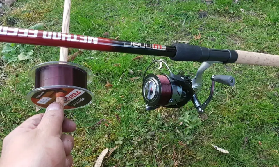 Wędka method feeder z kołowrotkiem i nową żyłką na trawie. Idealna żyłka do method feeder to podstawa udanego połowu.
