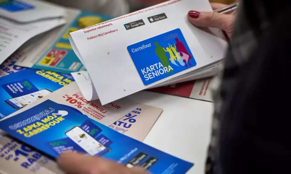 Karta Seniora Carrefour daje zniżki i rabaty. Na zdjęciu widać ulotki i kartę z logo Carrefour.