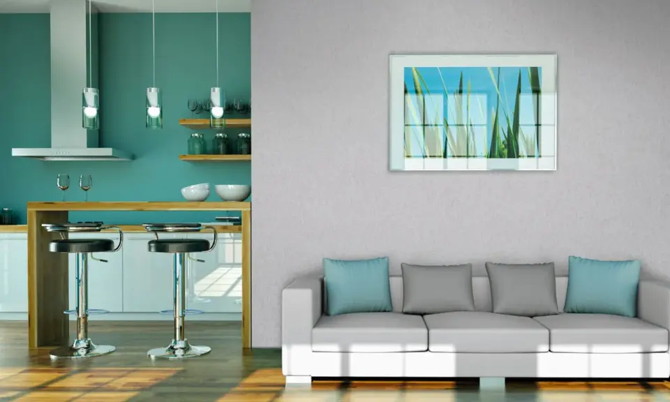 Modernes Wohnzimmer mit Vliestapete tapezieren. Ein weißes Sofa mit blauen und grauen Kissen steht vor einer Wand mit einem Bild von Gräsern. Daneben eine Küche mit Bar.