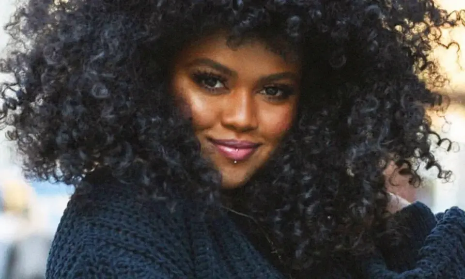A woman with voluminous, natural curly hair, showcasing beautiful hairstyles for natural curly hair.