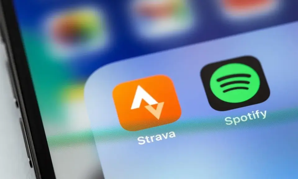 Ikona aplikacji Strava, idealna do śledzenia tras rowerowych, obok Spotify na ekranie smartfona.
