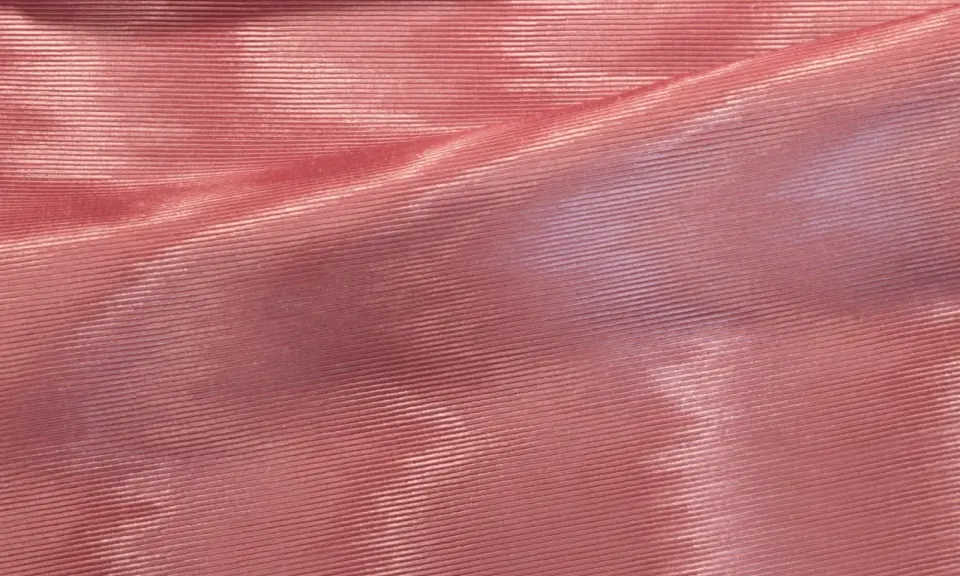 Tessuto rosa con pieghe che creano un affascinante effetto moiré, riflettendo la luce in modo cangiante.