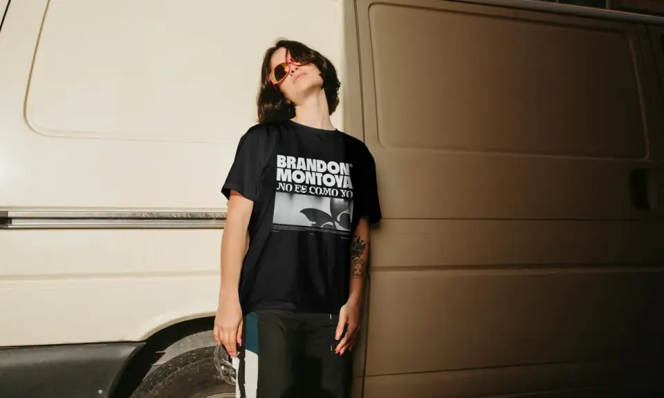 Joven con gafas de sol naranjas y camiseta negra con el diseño "BRANDON MONTOYA NO ES COMO YO".