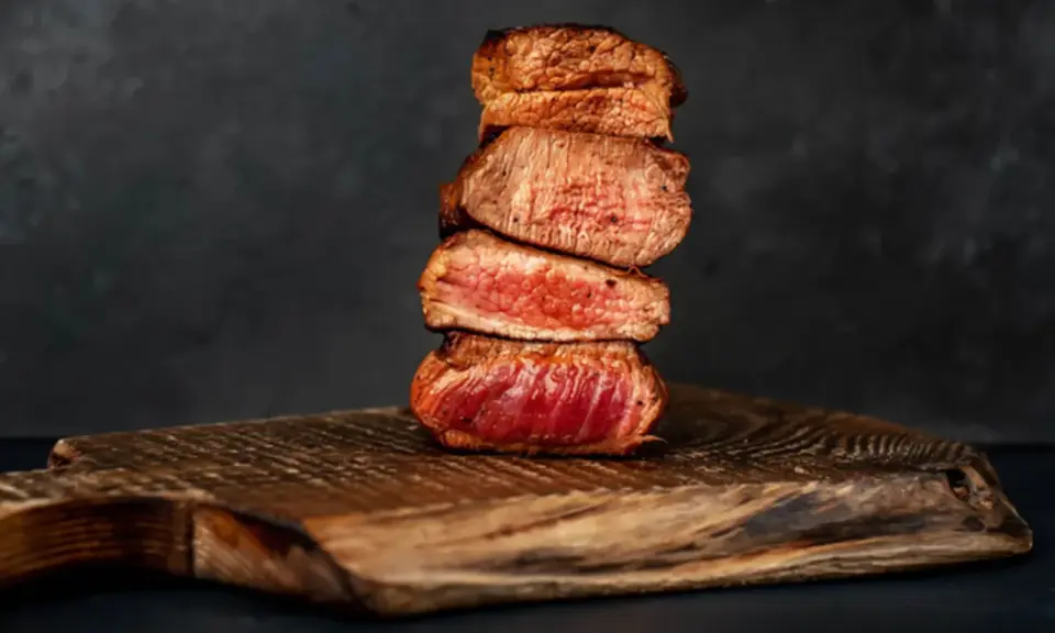 Gestapelte, saftige Steak-Scheiben, perfekt englisch gebraten, auf einem rustikalen Holzbrett.