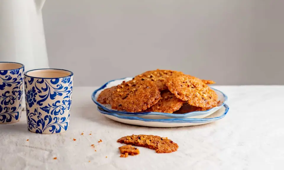 Deliciosas galletas de jengibre con trozos de nuez, servidas en un plato azul y blanco. Perfectas para acompañar un café.