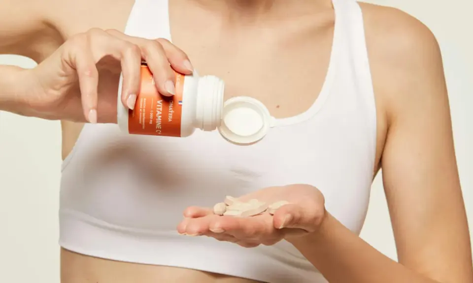 Une main verse des comprimés de vitamine C dans l'autre main, pour une cure revitalisante.