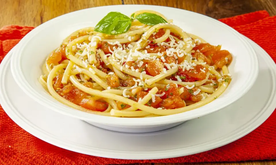 Un piatto invitante di pasta alla carrettiera, con pomodoro fresco, basilico e abbondante formaggio grattugiato.