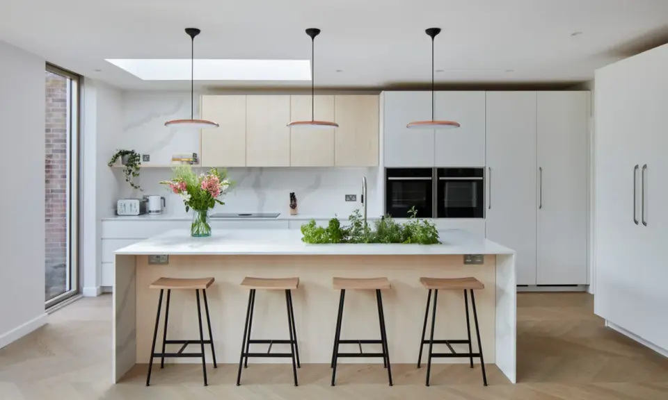 Cuisine moderne avec îlot central, tabourets en bois et une niche ouverte intégrée dans les placards.
