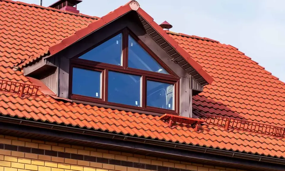 Ein Dachfenster mit dreieckigem Oberlicht und roten Ziegeln. Informieren Sie sich, was kostet eine gaube für Ihr Haus.