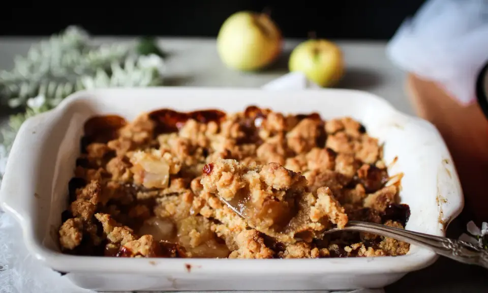 Une cuillère prélève une portion généreuse de ce vrai recette crumble aux pommes caramélisées, fondant et croustillant.
