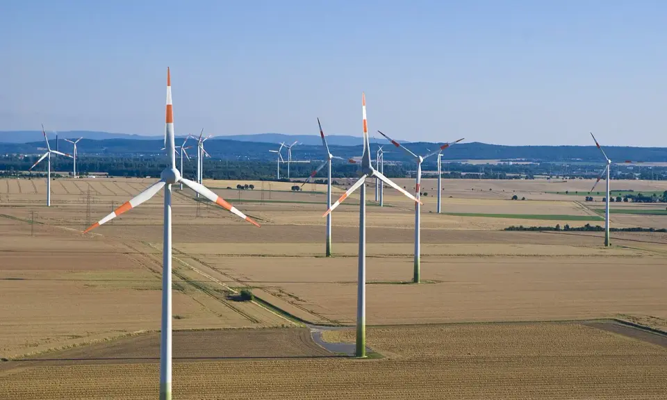 Großer onshore windpark in einer weiten Feldlandschaft unter blauem Himmel.