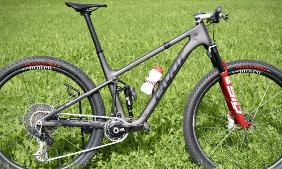 Ein graues Mountainbike mit roten Akzenten auf der Gabel und einer Trinkflasche. Die Reifen tragen die Aufschrift "Phantom Proven". Ein tolles Rad für die letzten Bikes der Saison.