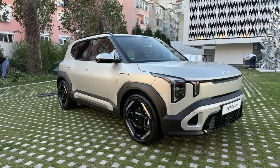El ev2 kia, un SUV eléctrico plateado, descansa sobre un césped con baldosas cuadradas.