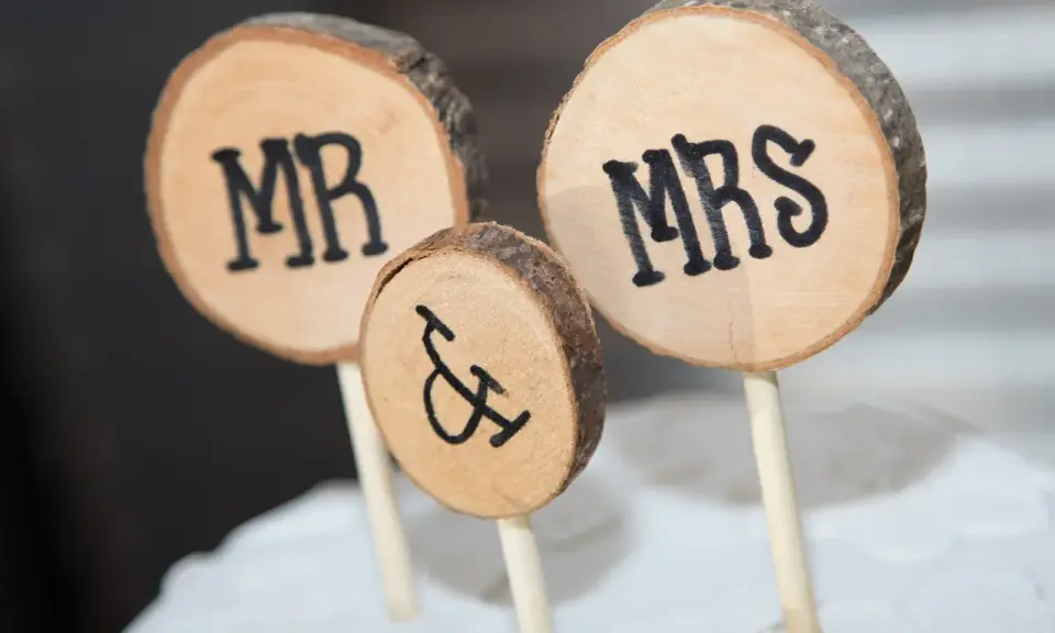 Drewniane krążki z napisami MR i MRS, symbolizujące Parę Młodą, ozdabiają tort.