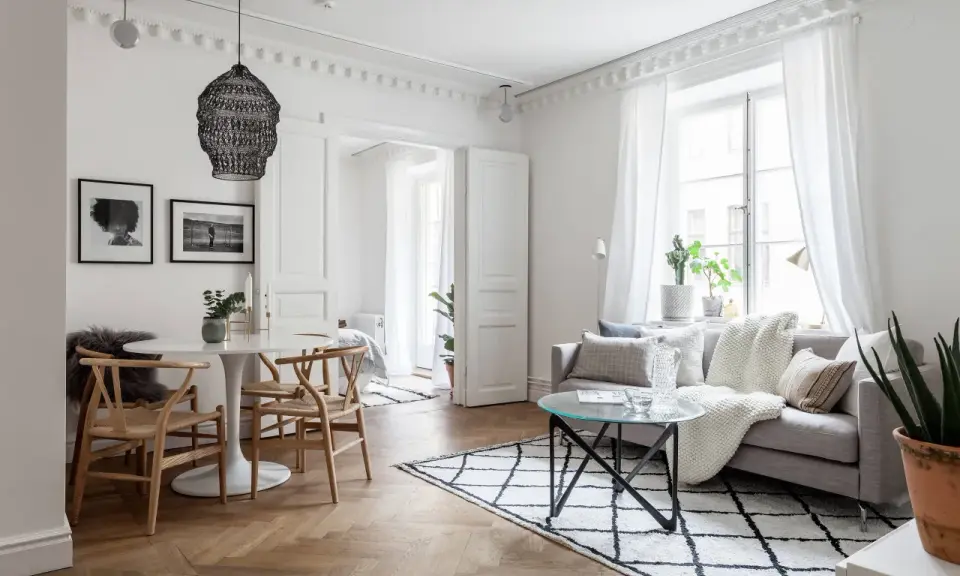 Ljust och luftigt vardagsrum med matbord och inspiration från skandinavisk design. En rund vit matplats med trästolar möter en soffgrupp med mysiga textilier.