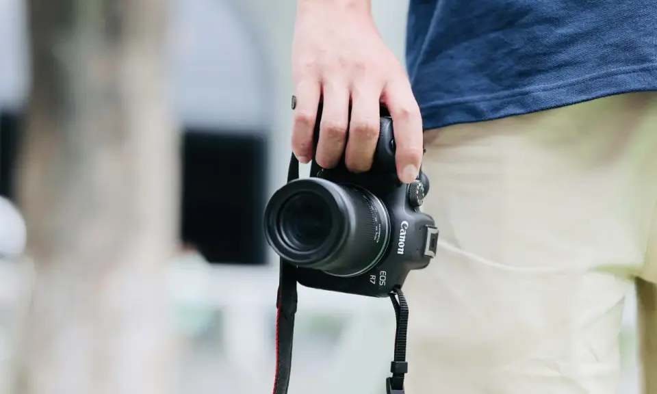 Dłoń trzyma aparat Canon EOS R7, gotowy do uchwycenia chwili. Jego matryca w aparacie zapewni doskonałą jakość zdjęć.