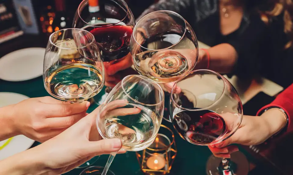 Ludzie wznoszą toasty winem. Pamiętaj o odpowiedzialnym spożywaniu alkoholu, zwłaszcza gdy rozważasz antykoncepcję.