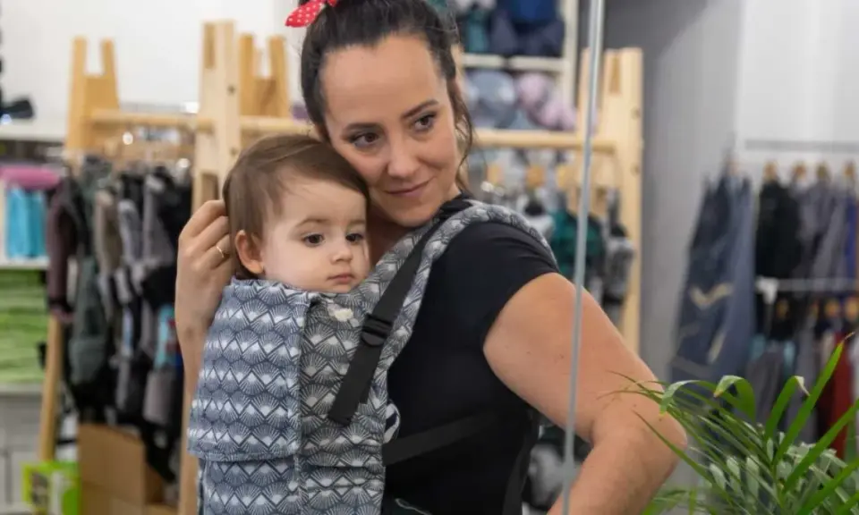 Mama wybiera jakie nosidełko dla 5 miesięcznego niemowlaka. Dziecko w nosidle z wzorem.