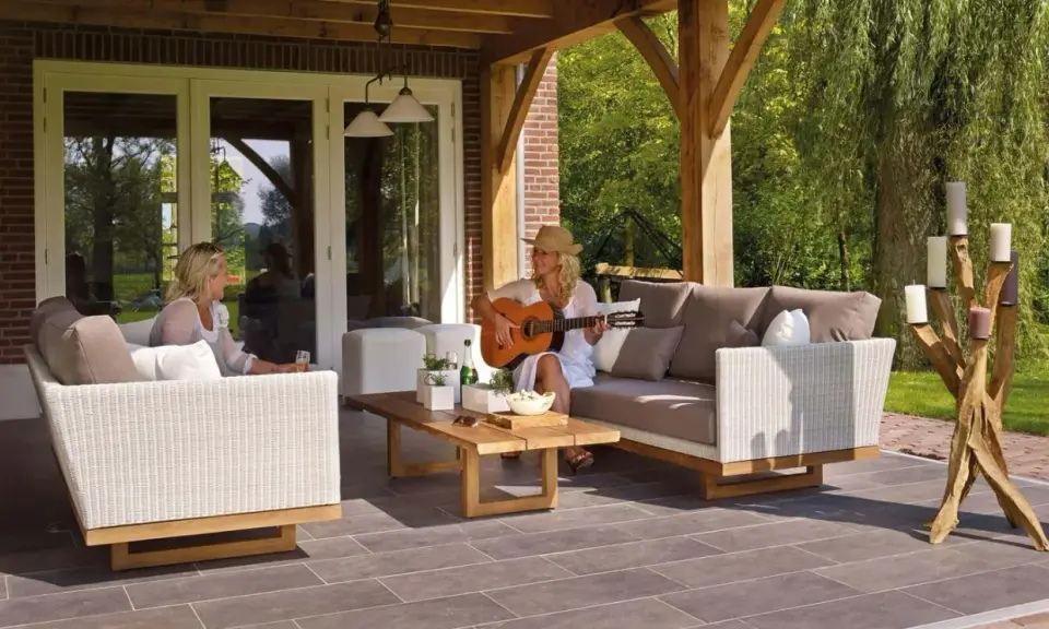 Kobieta gra na gitarze na tarasie, siedząc na sofie obok koleżanki. To idealne miejsce na relaks, jakby to był prywatny balkon.