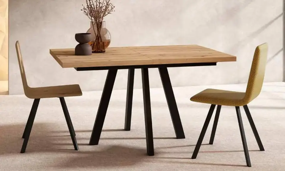 Mesa comedor extensible de madera con patas metálicas negras, ideal para ampliar el espacio. Dos sillas modernas flanquean la mesa.