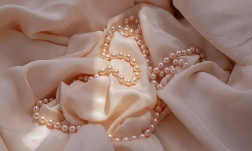 Un filo di perle rosa pallido adagiato su una morbida seta color crema. Un'idea perfetta per regalare perle.