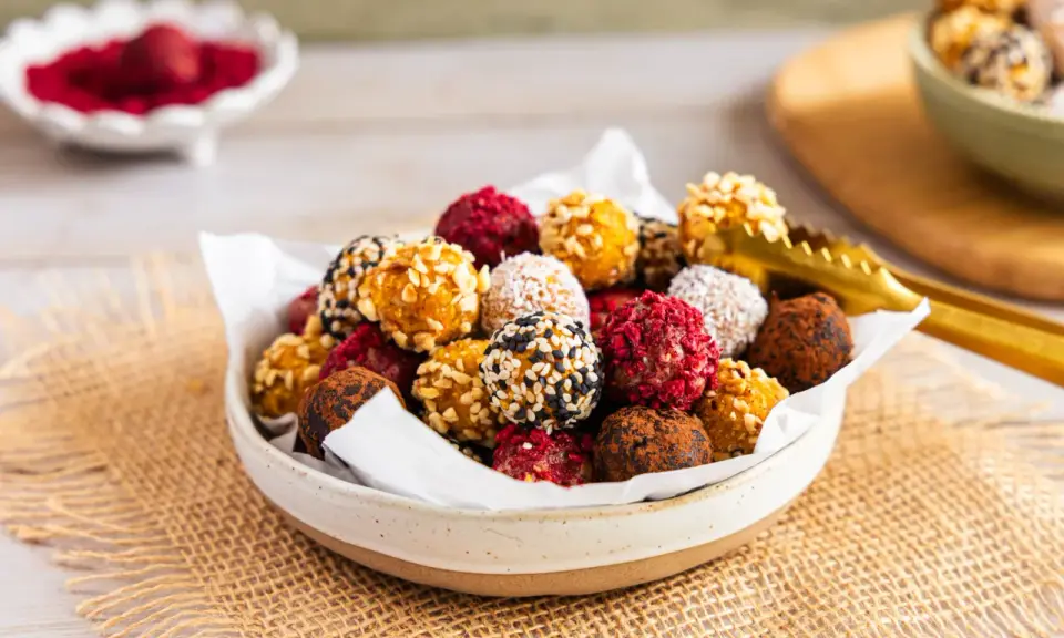 Schüssel voller bunter Energy Balls, perfekt für ein schnelles energy balls rezept. Mit Nüssen, Kokos, Kakao und Beeren verfeinert.