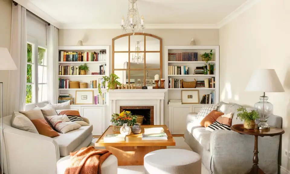 Un salón acogedor con sofás blancos y madera, sobre un fondo de color de pared para muebles blancos y madera.