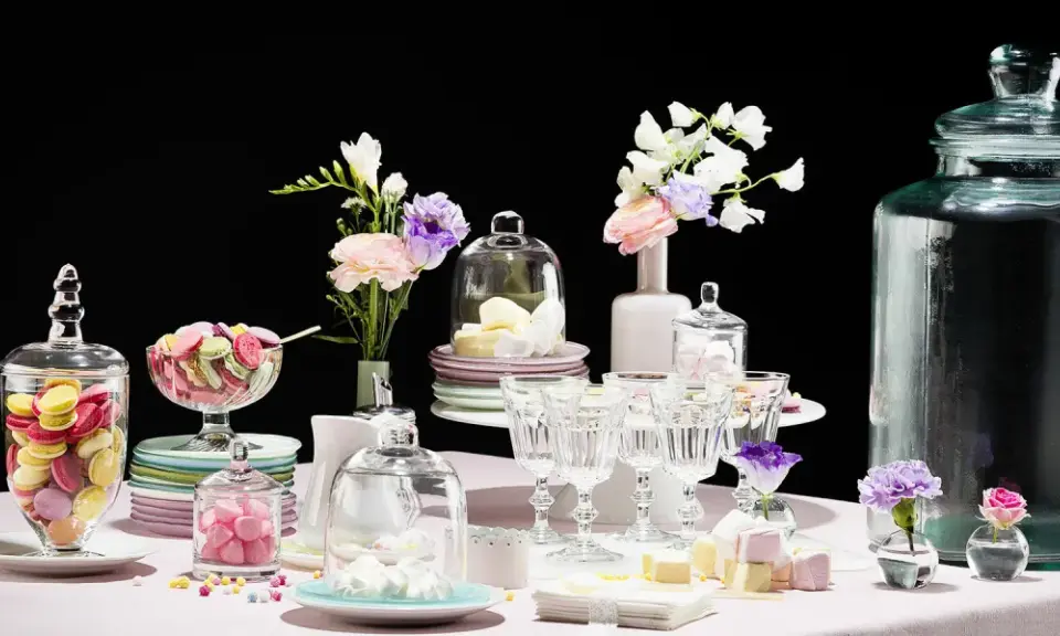 Buffet vin d'honneur fait maison : macarons colorés, meringues, guimauves et fleurs dans des vases.