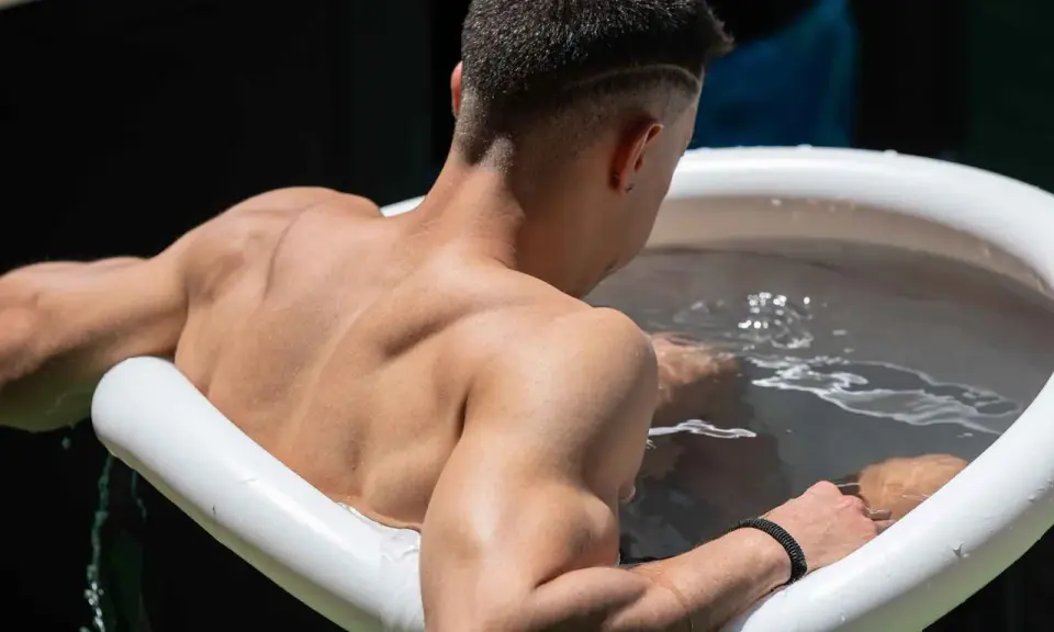 Mann sitzt im Eisbad, bereit für das warme Duschen danach.