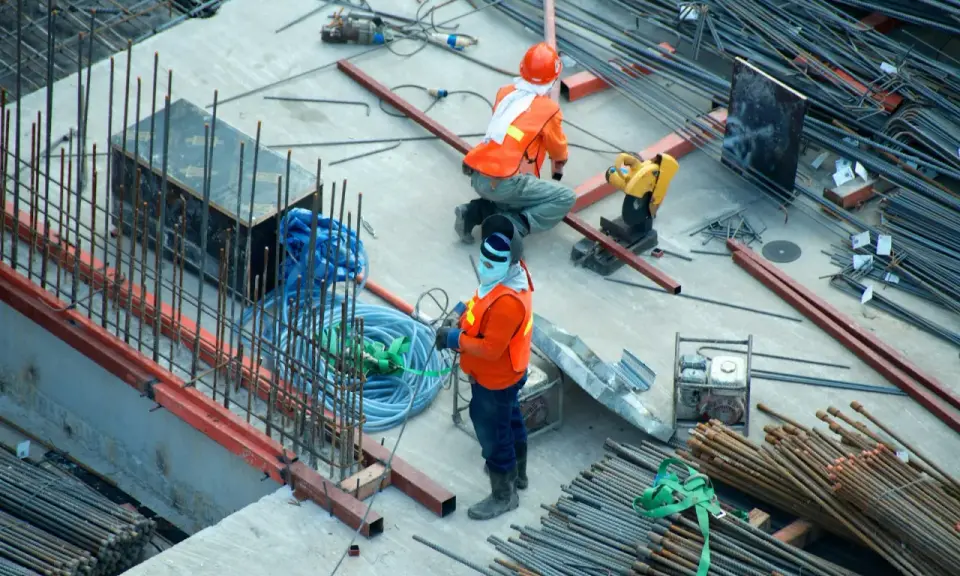 Budowa domu to proces, który wymaga czasu i pracy. Na placu budowy widać robotników i materiały.