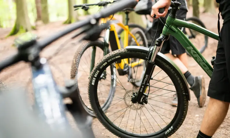 Przygotowania do amatorskich rajdów rowerowych w lesie. Dwa rowery górskie, jeden zielony, drugi żółty, stoją na leśnej ścieżce.