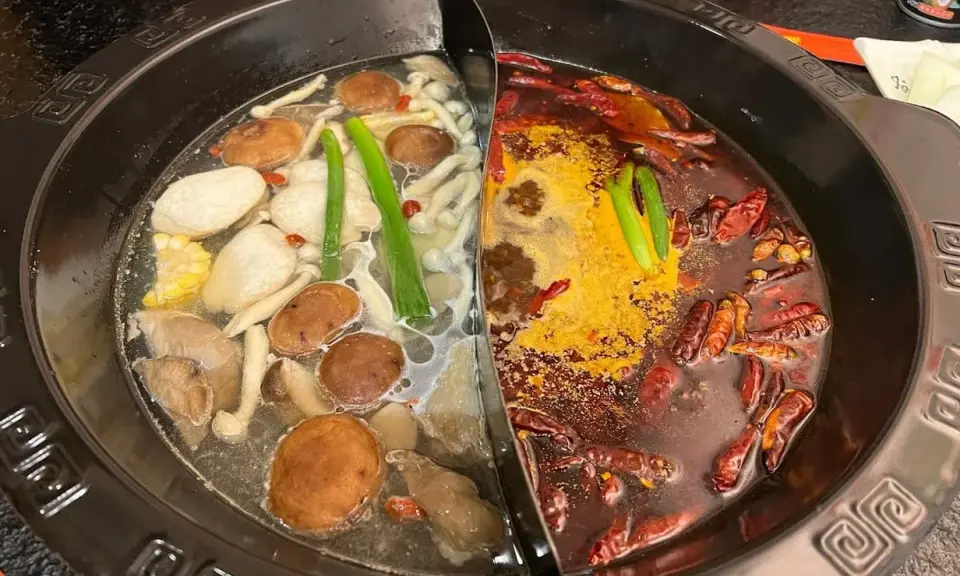 Une fondue chinoise à deux bouillons : un clair avec champignons et légumes, l'autre épicé aux piments.
